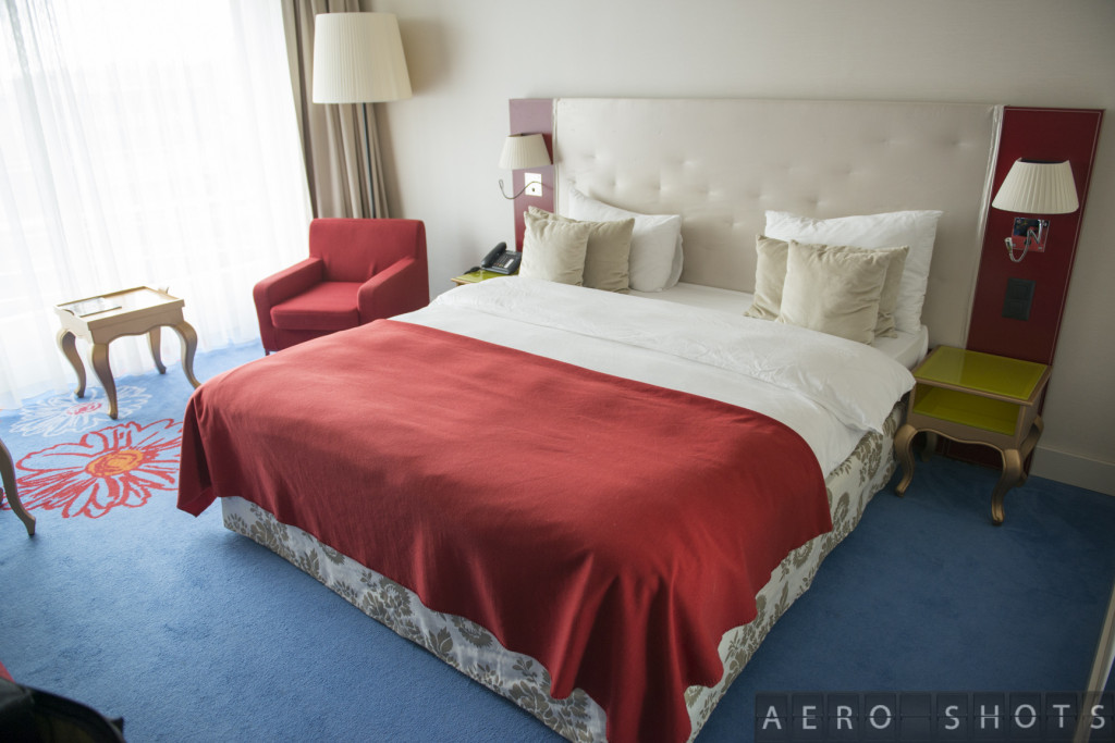 a bed with a red blanket and a chair in a room