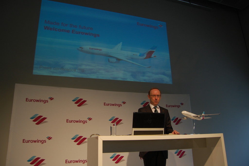 a man standing at a podium with a laptop and a model airplane on it