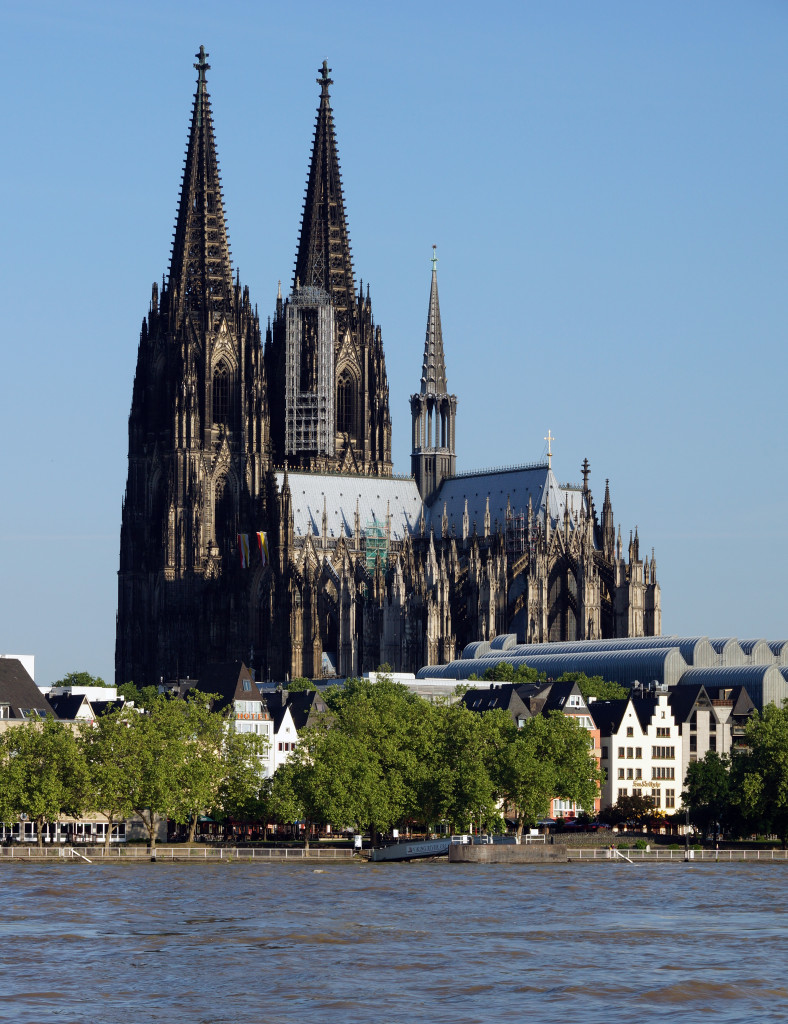 a large building with towers and a body of water with Cologne Cathedral in the background