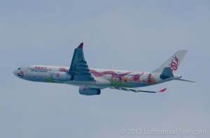 a white airplane with red and white dragon designs flying in the sky