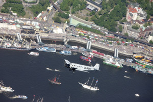an airplane flying over water with boats and buildings
