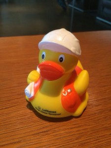a yellow rubber duck with a white hat on a wooden surface