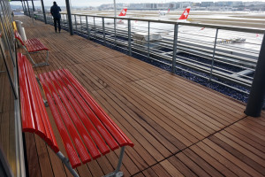 a wooden deck with red benches and a person walking