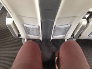 a person's legs and a pair of legs in an airplane