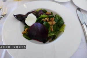 a salad with beets and cheese on a white plate