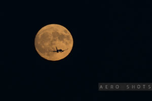 an airplane flying in the sky with the moon