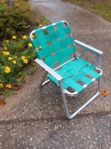 a green chair on a sidewalk